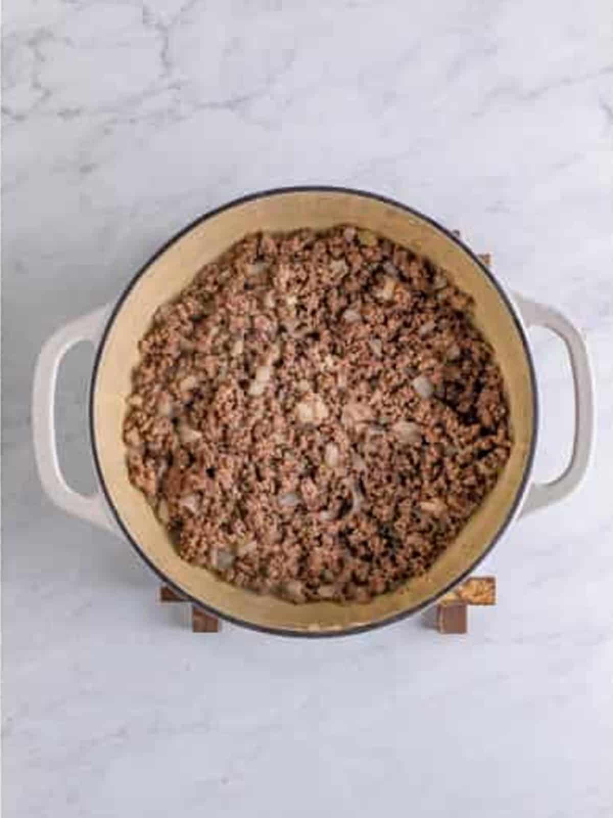 Ground beef and onions browned in a Dutch oven for hot dog chili.