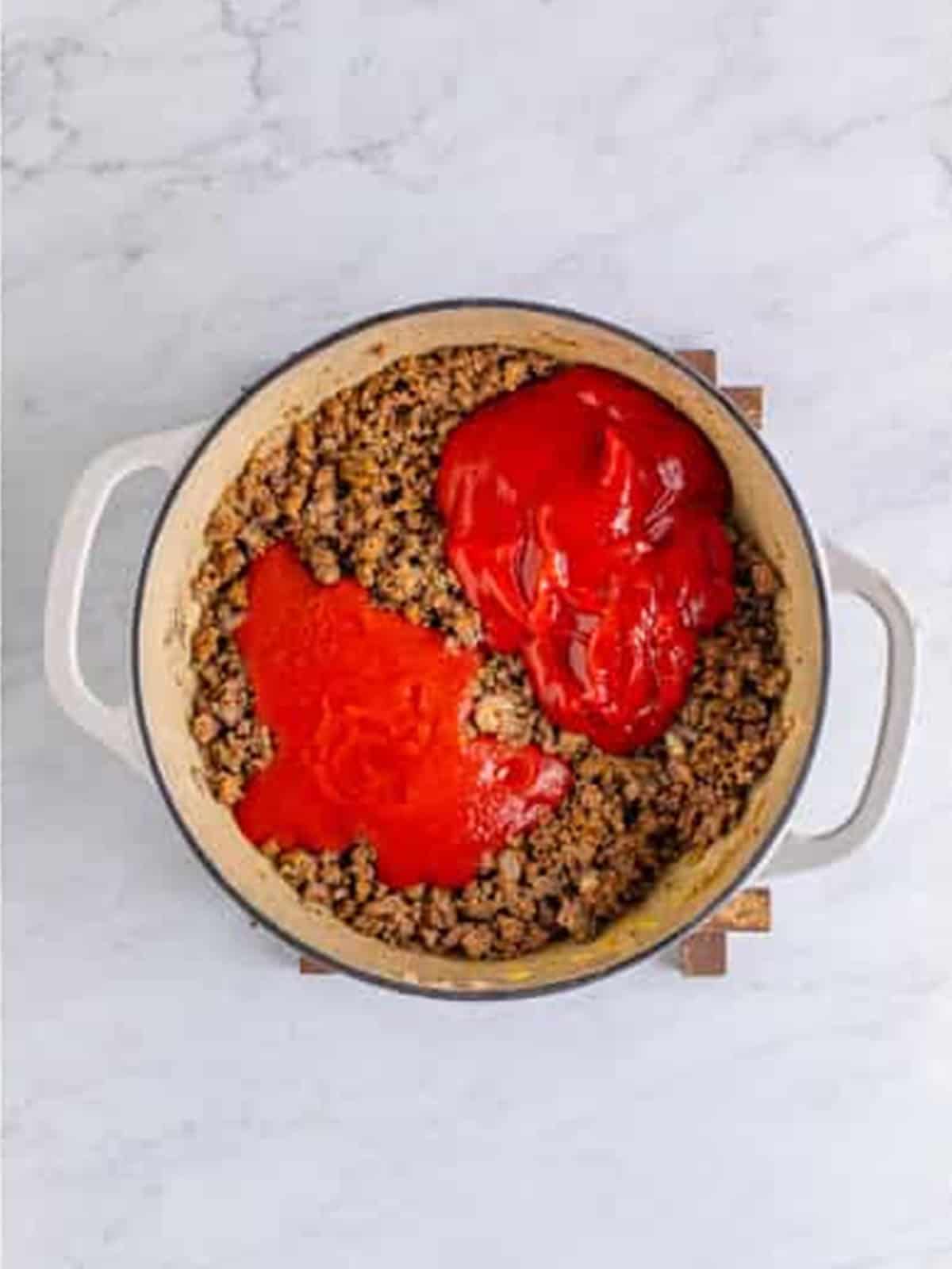Ketchup and tomato sauce added to the seasoned beef for hot dog chili.