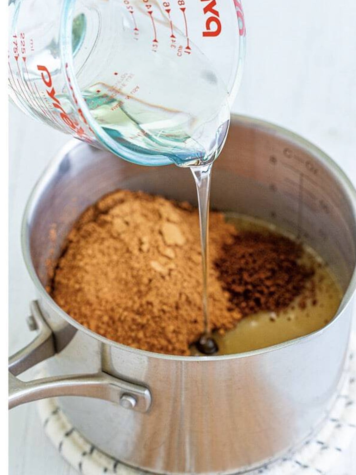 Brown sugar, cocoa, and corn syrup added to a saucepan for hot fudge sauce.
