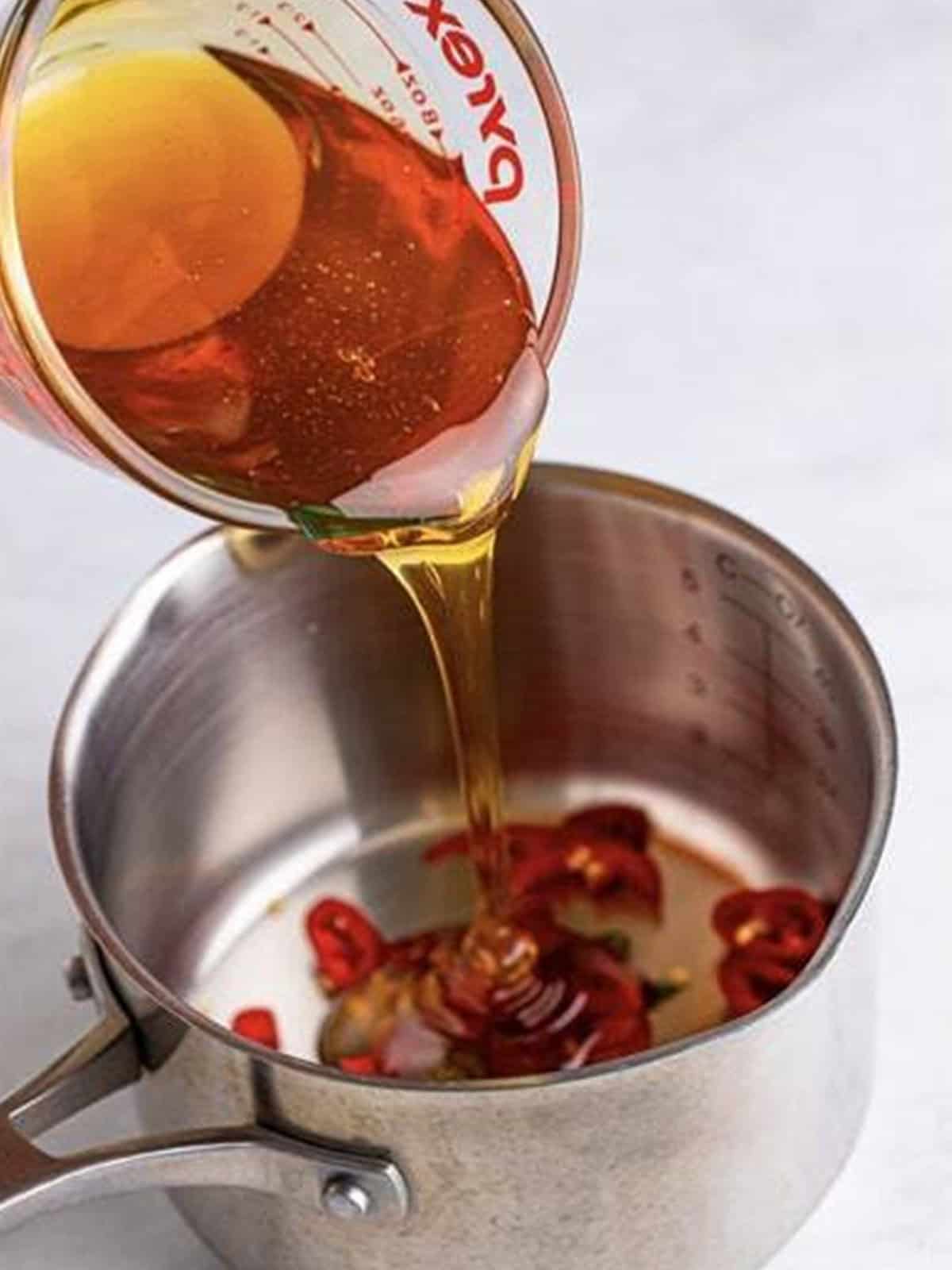 Sliced Fresno and Thai chiles and honey combined in a small saucepan.