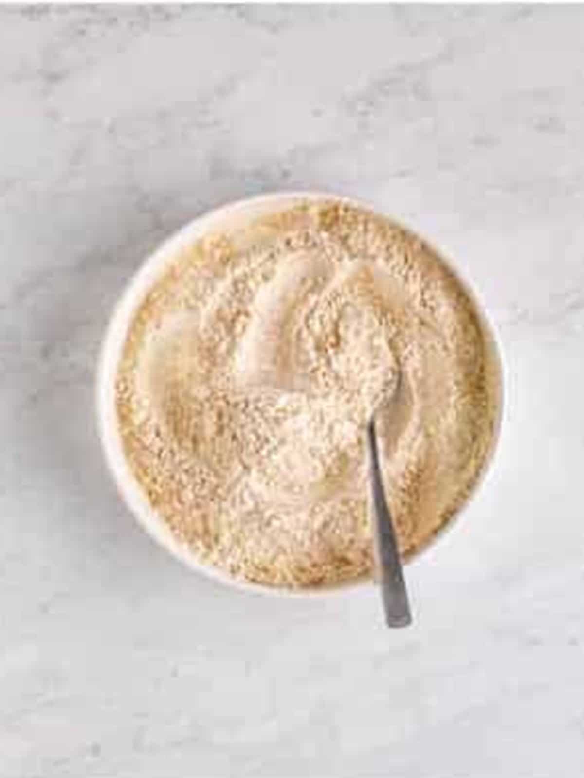Whisking together flour, cinnamon, baking soda, and salt in a white bowl.