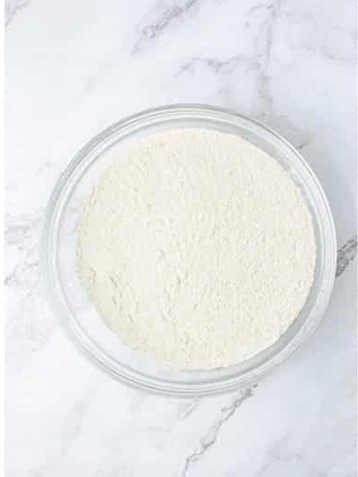 Flour, sugar, baking soda, and salt whisked together in a bowl for hummingbird cake.