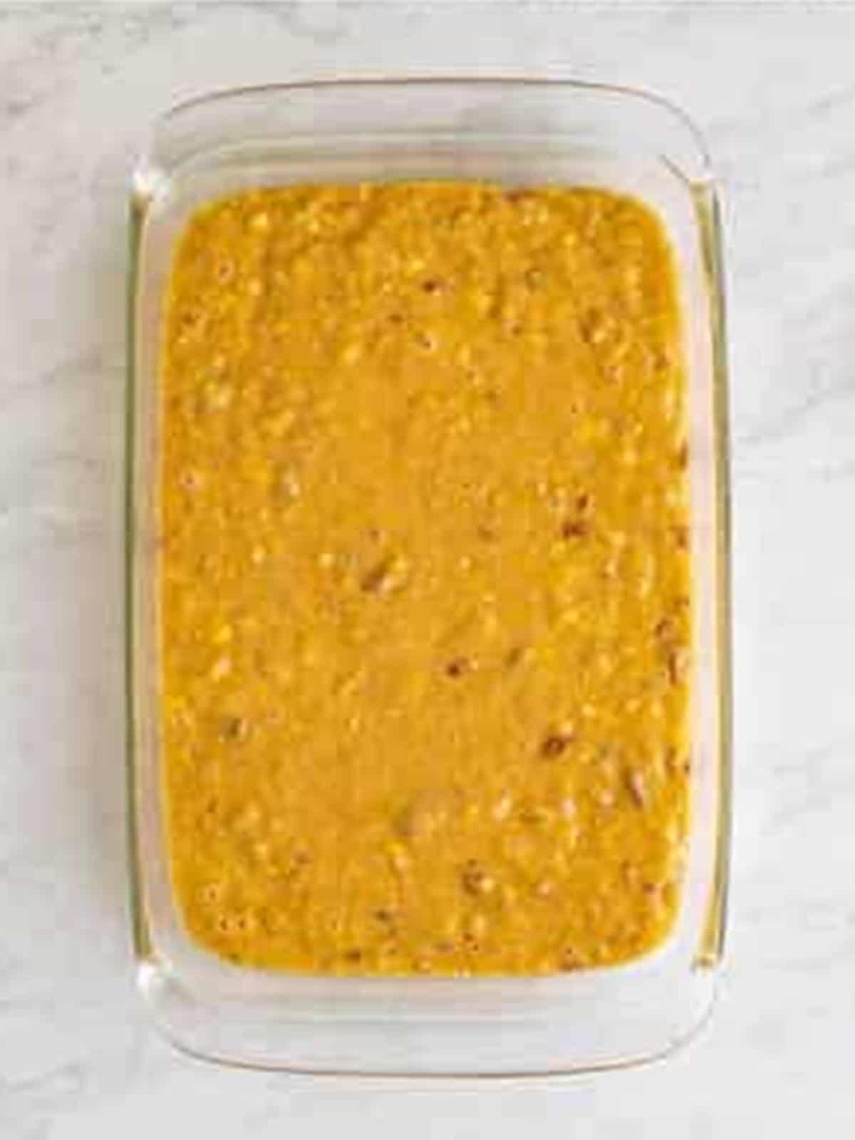 Spreading Hummingbird Cake batter into a glass nine by thirteen baking dish.