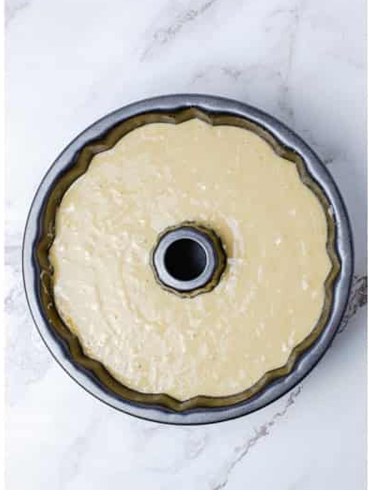 Hummingbird cake batter spooned into a greased bundt pan.