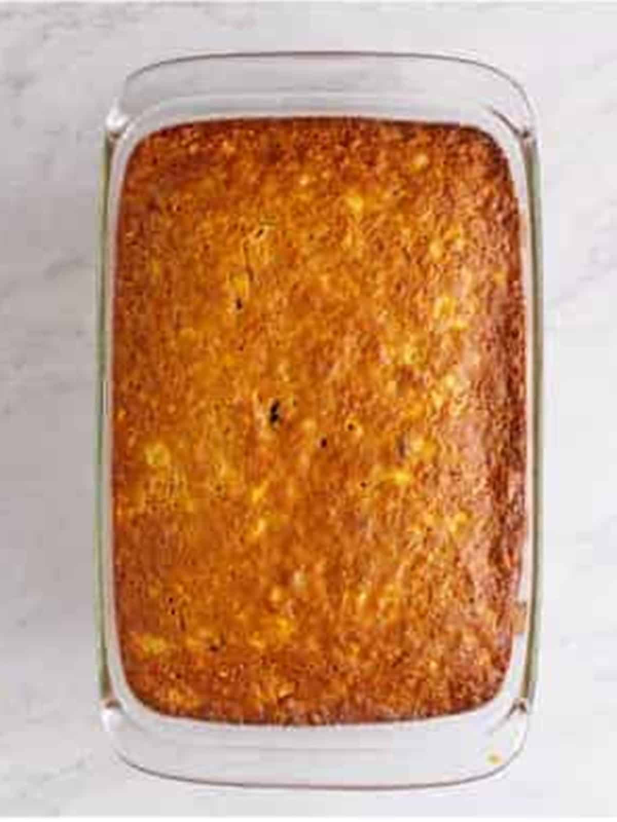 Baked golden Hummingbird Cake cooling in a glass baking dish.