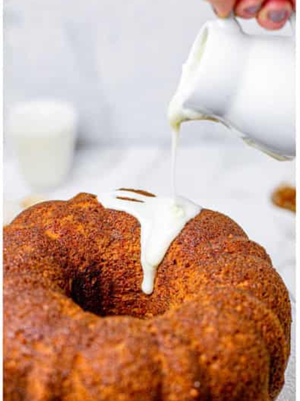 Cream cheese glaze being poured over a cooled hummingbird bundt cake.