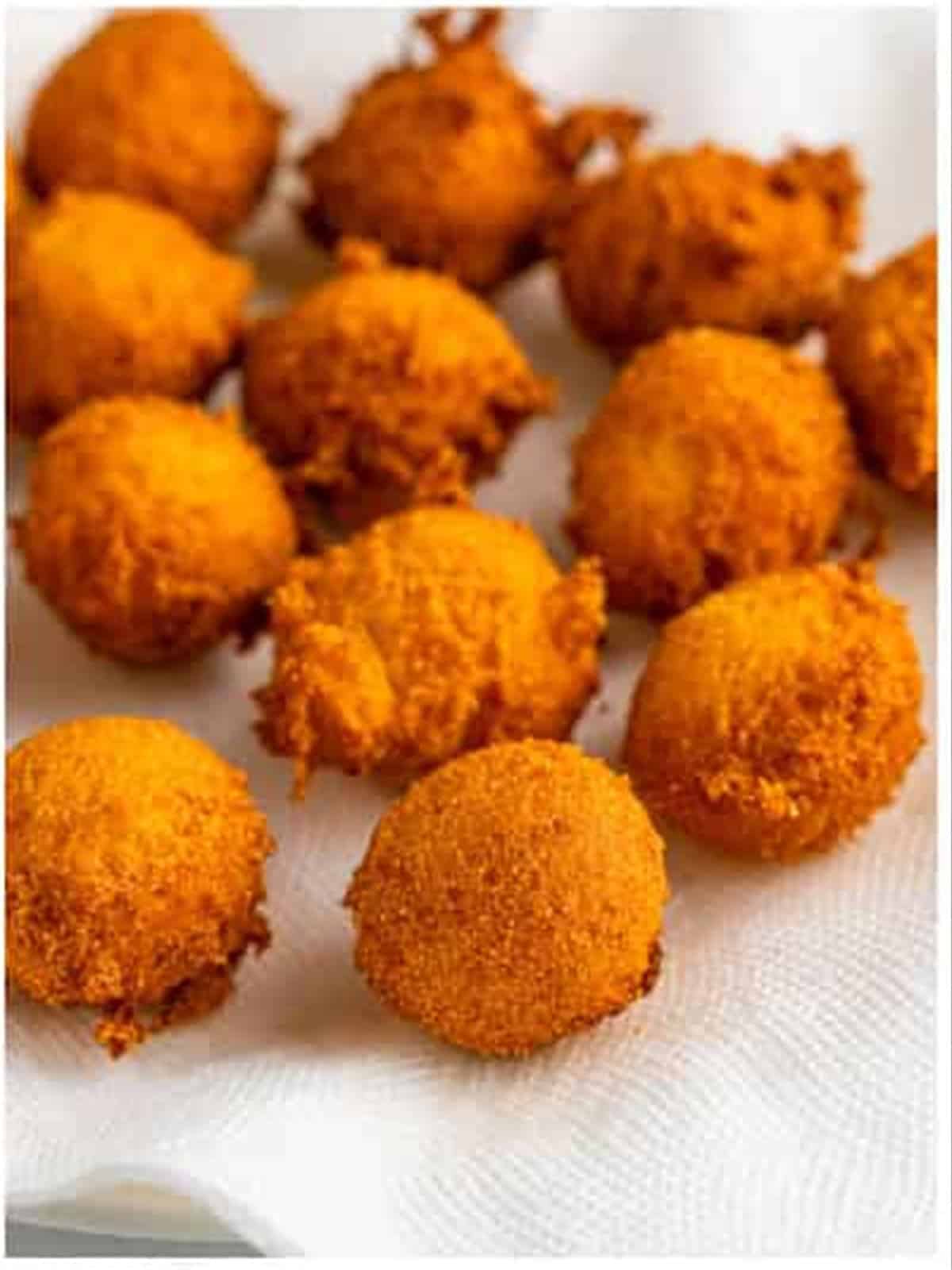 Golden fried hush puppies draining on paper towels.