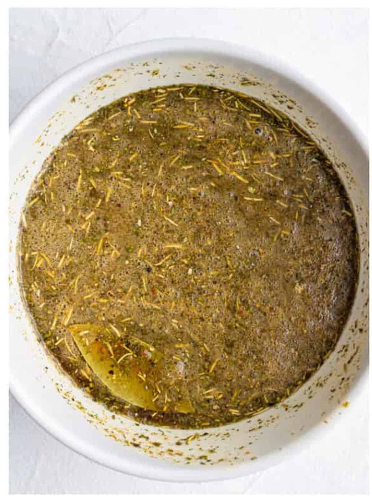 Beef broth combined with Italian seasonings and dressing mix in a bowl.
