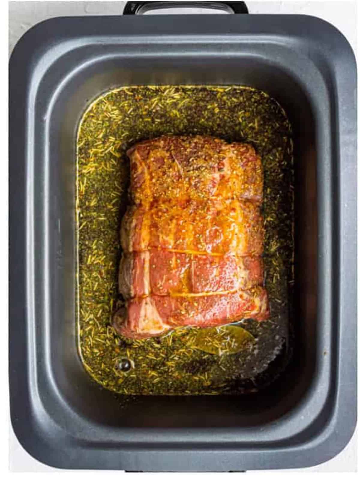 Seasoned broth, giardiniera, and pepperoncini poured over the roast in the slow cooker.