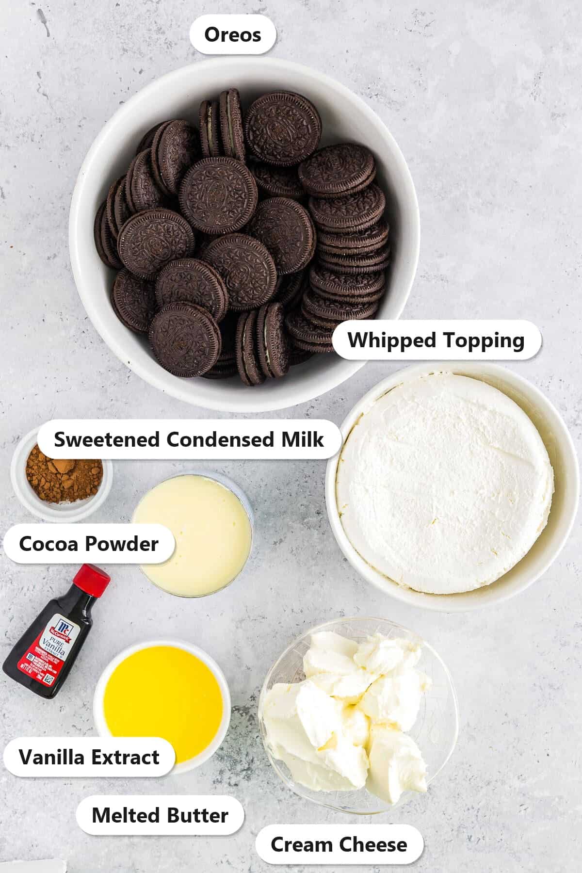 Labeled ingredients for ice cream dirt cake including Oreos, cream cheese, sweetened condensed milk, whipped topping, melted butter, cocoa powder, and vanilla extract.