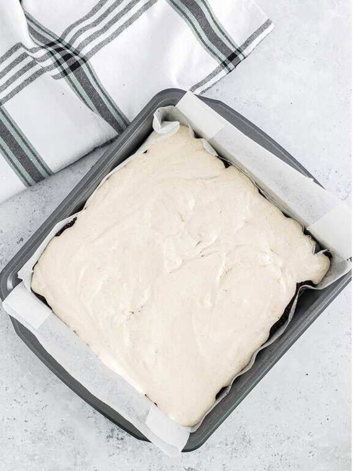 Cocoa filling layer spread over the cookie crumbs in the frozen dirt cake.