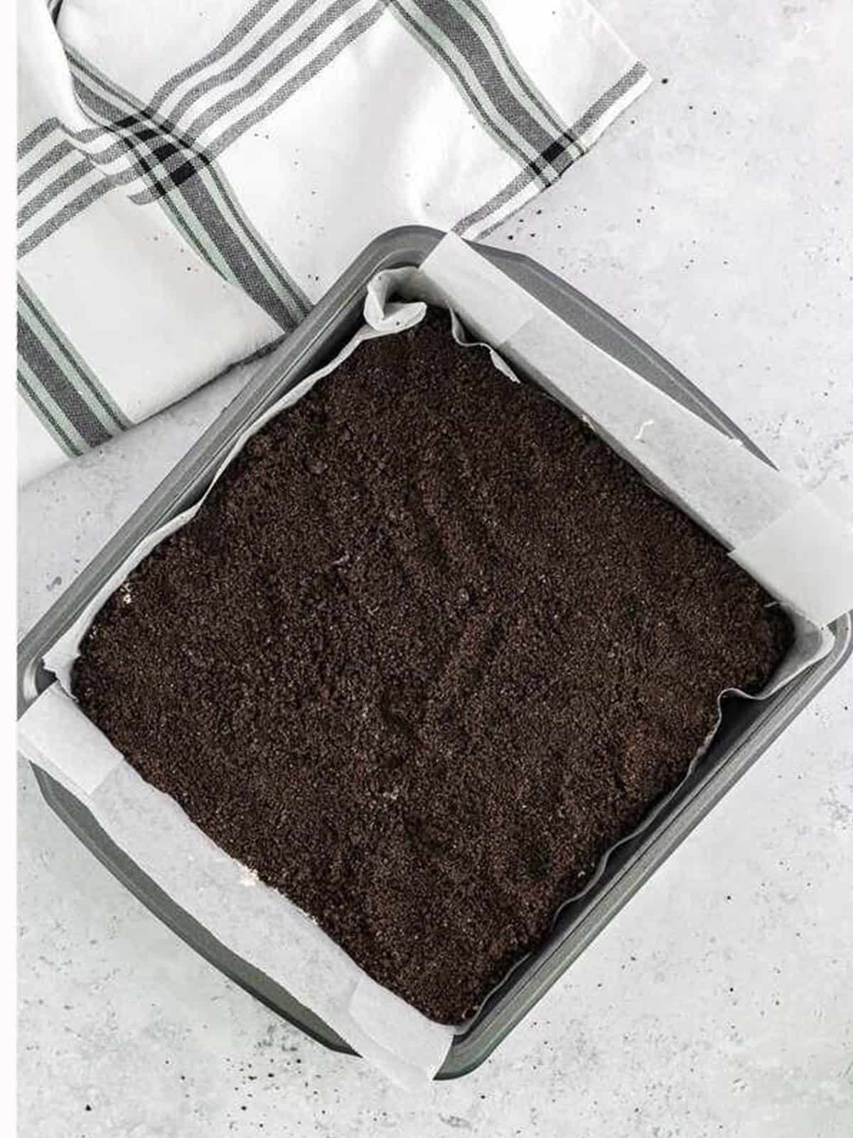 Final layer of Oreo crumbs covering the ice cream dirt cake before freezing.