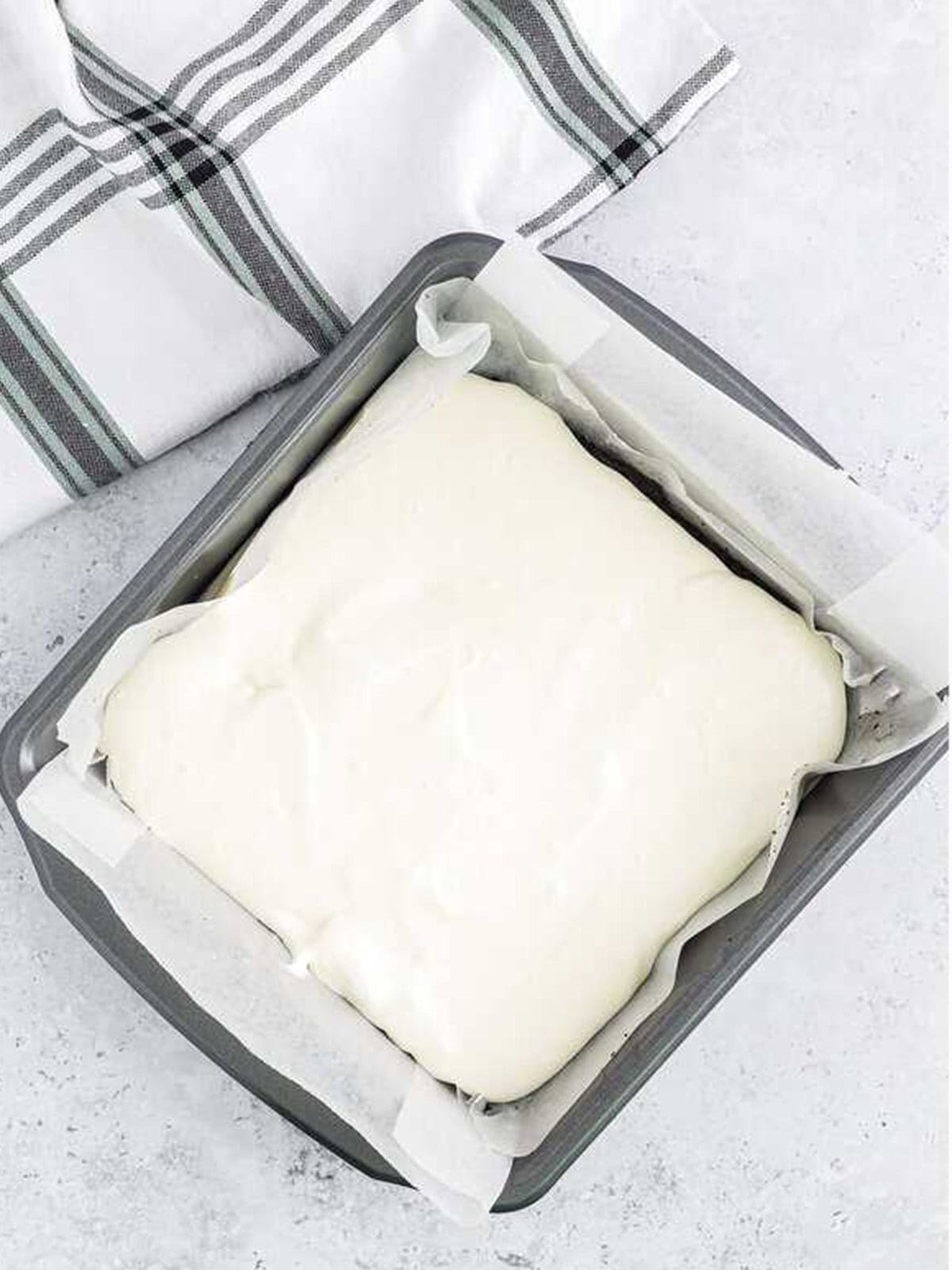 Half of the vanilla filling spread over the Oreo crust in the pan.
