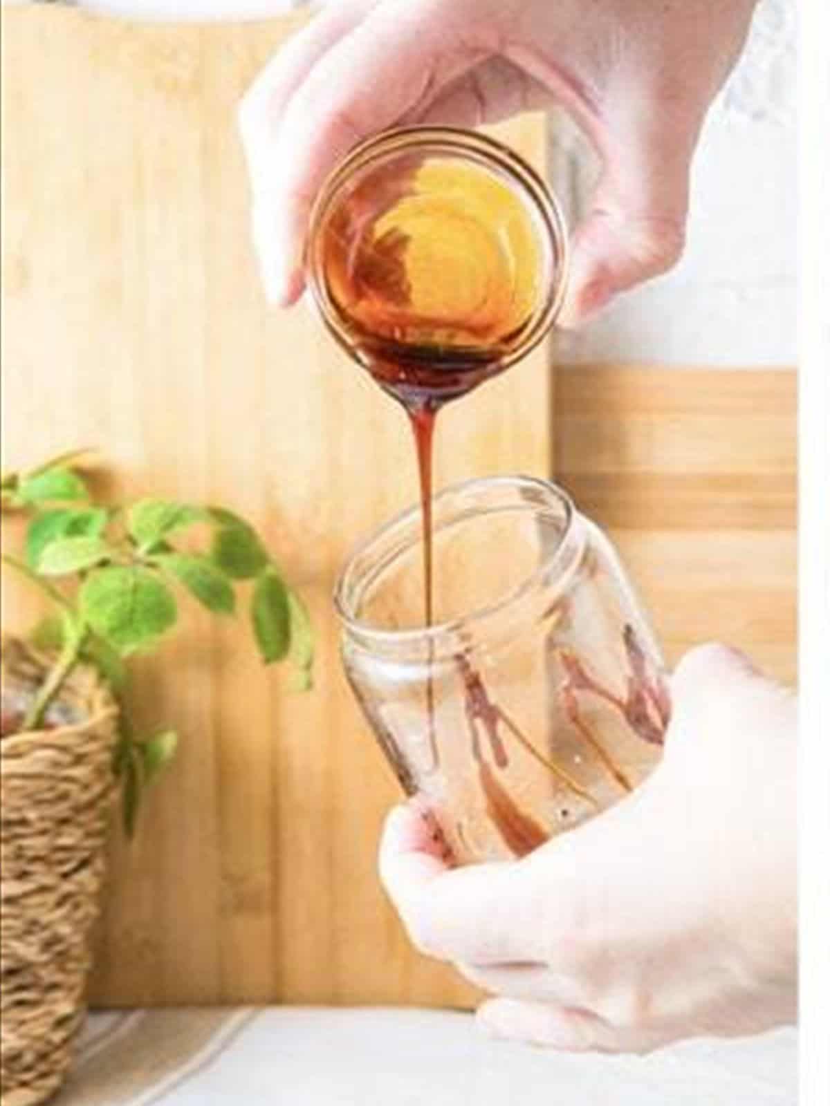 Pouring the frothy coffee mixture into a glass for an iced caramel latte.