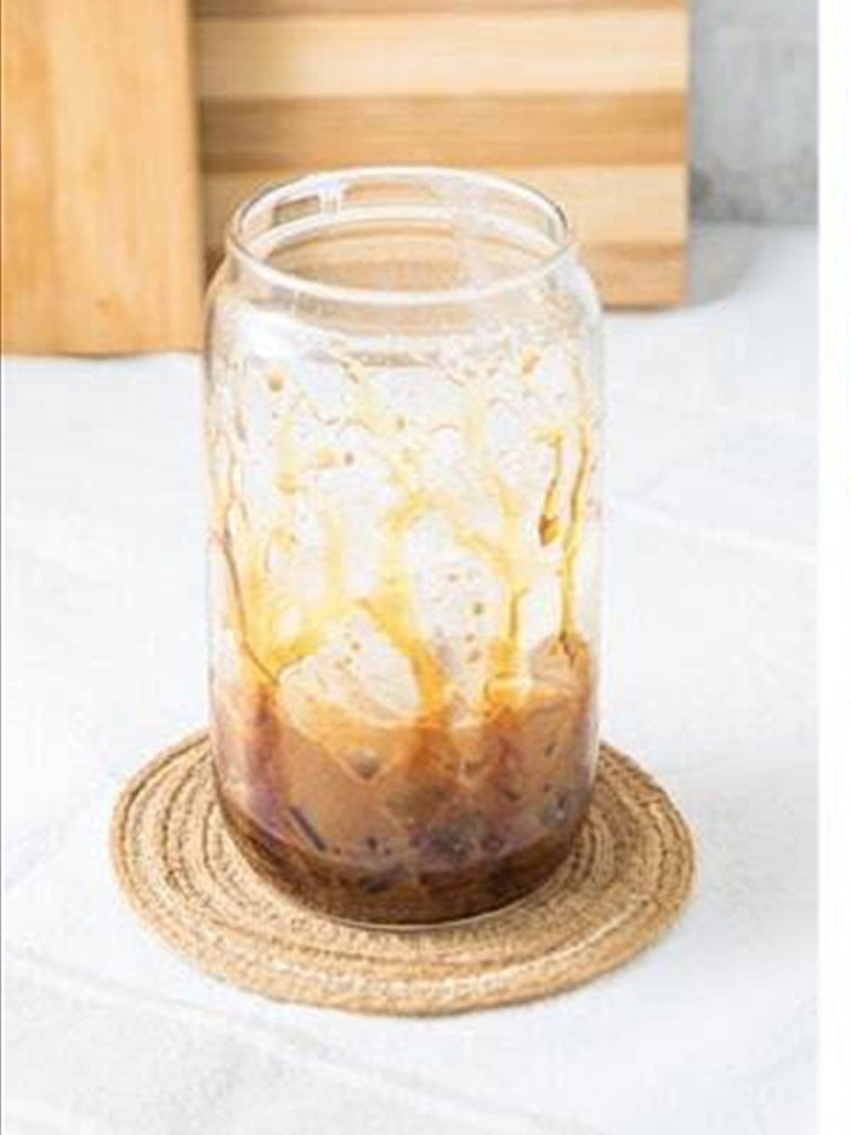 Adding ice to the caramel lined glass for an iced caramel latte.