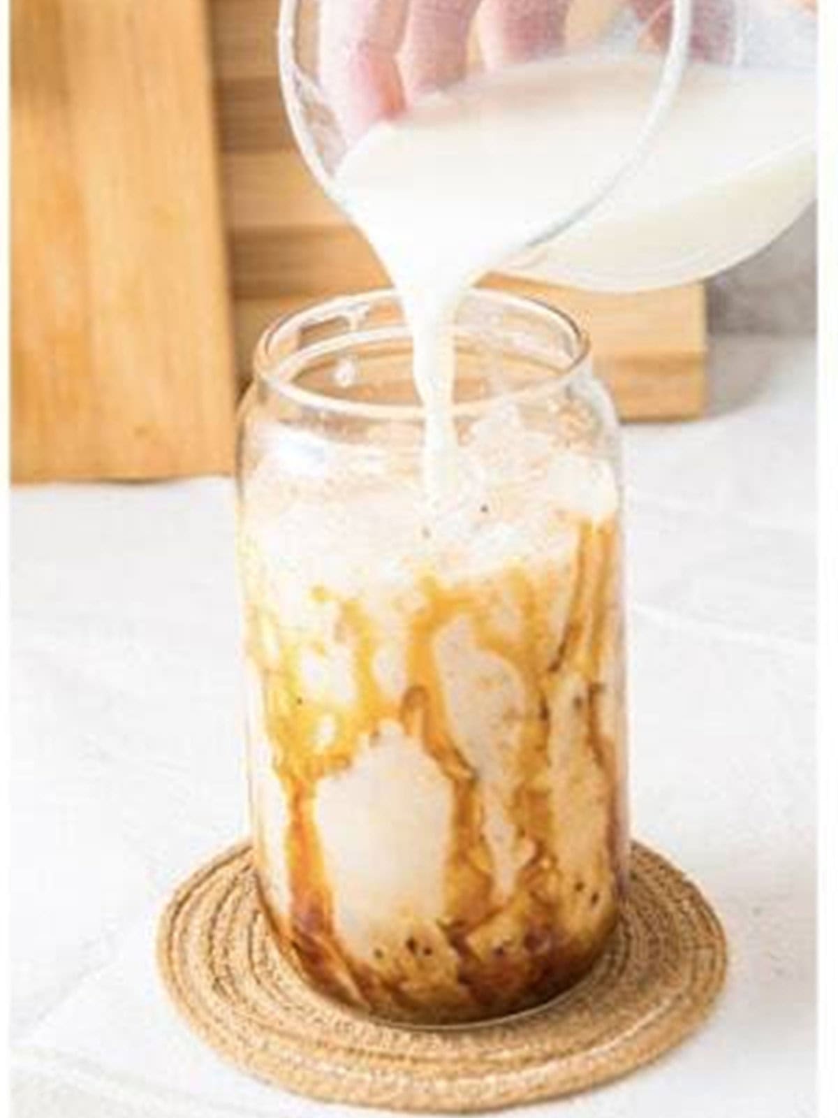 Pouring milk over ice for an iced caramel latte.