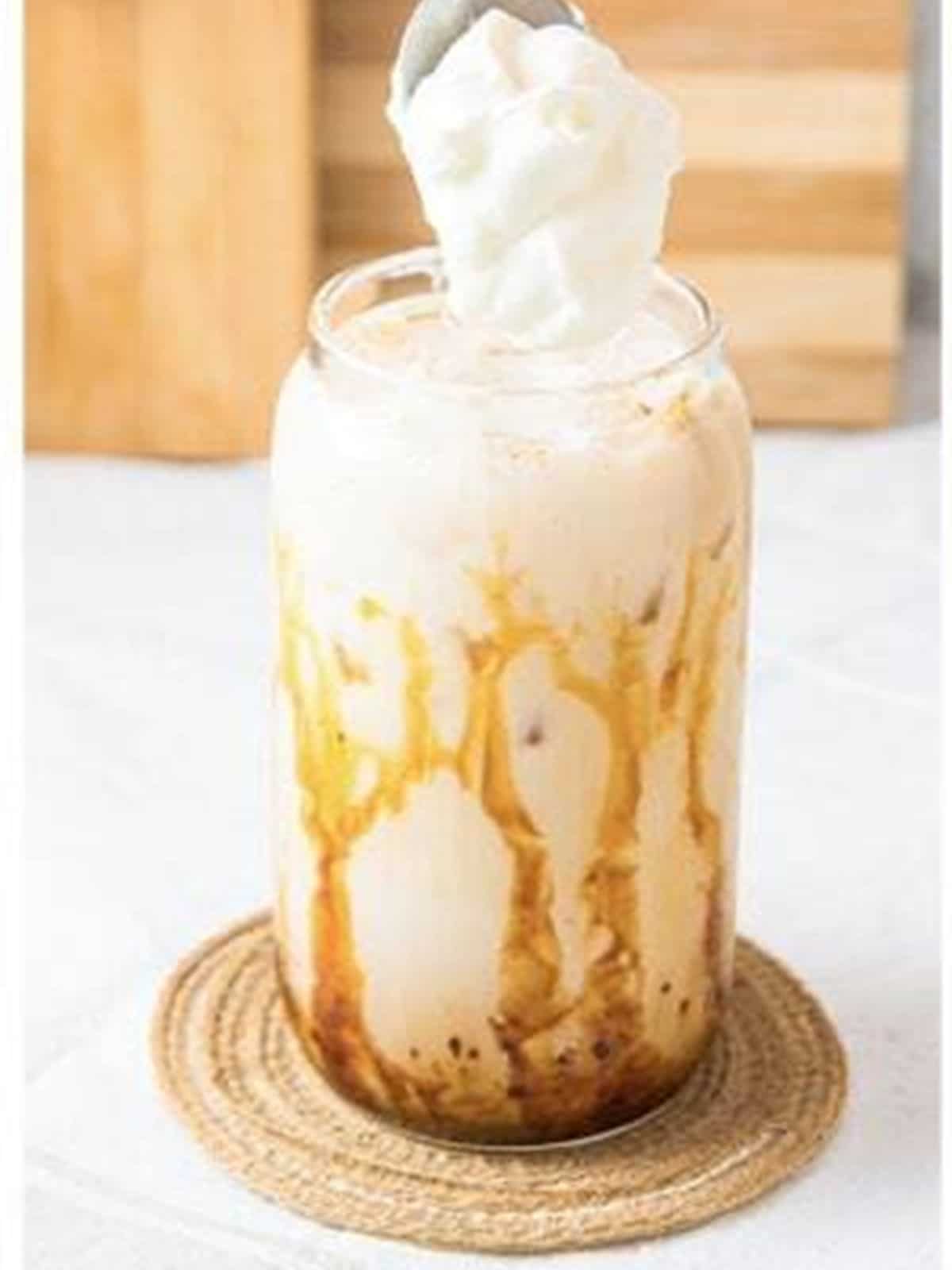 Topping the iced caramel latte with whipped cream.