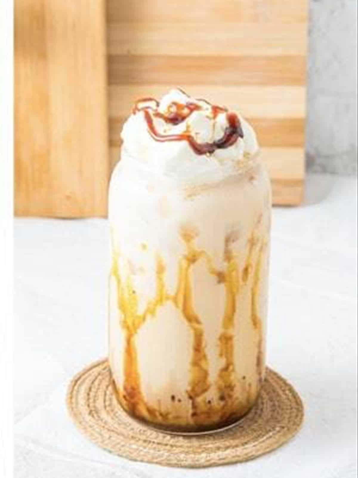 Finished iced caramel latte drizzled with caramel sauce.