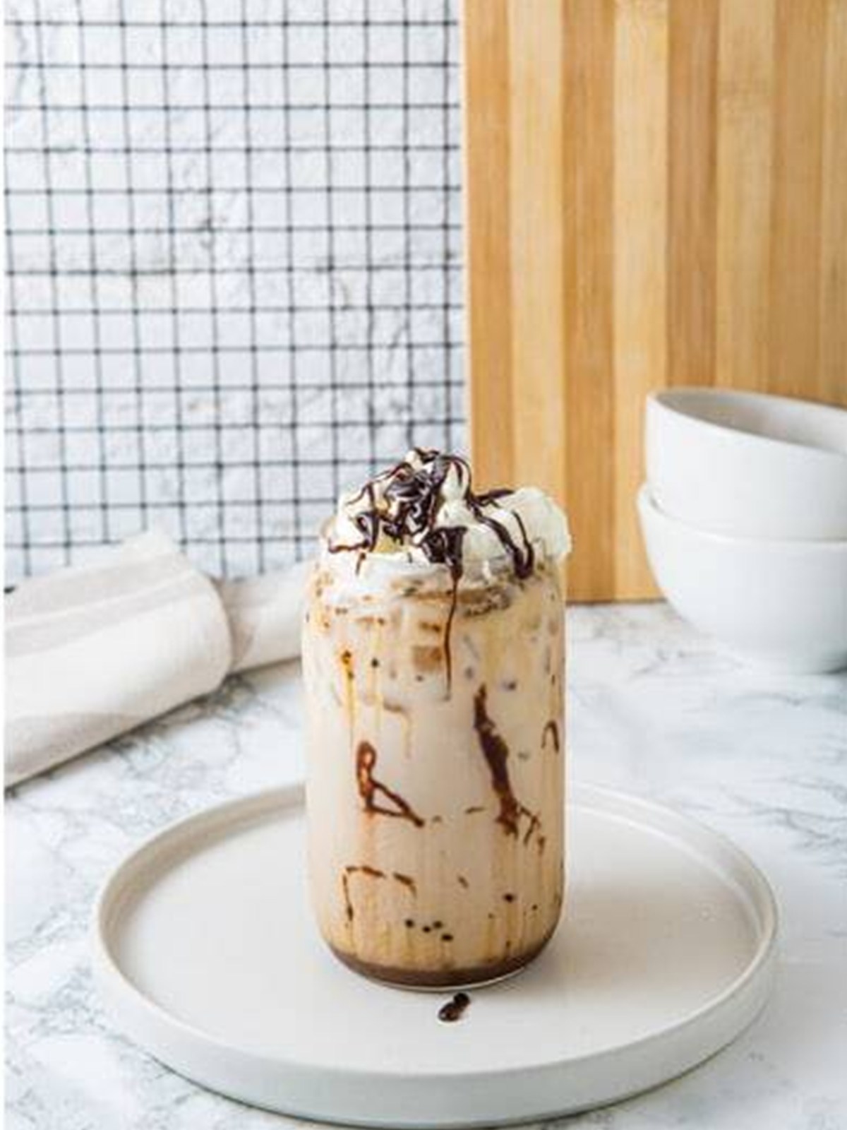 Drizzling chocolate syrup over the finished Iced Mocha.