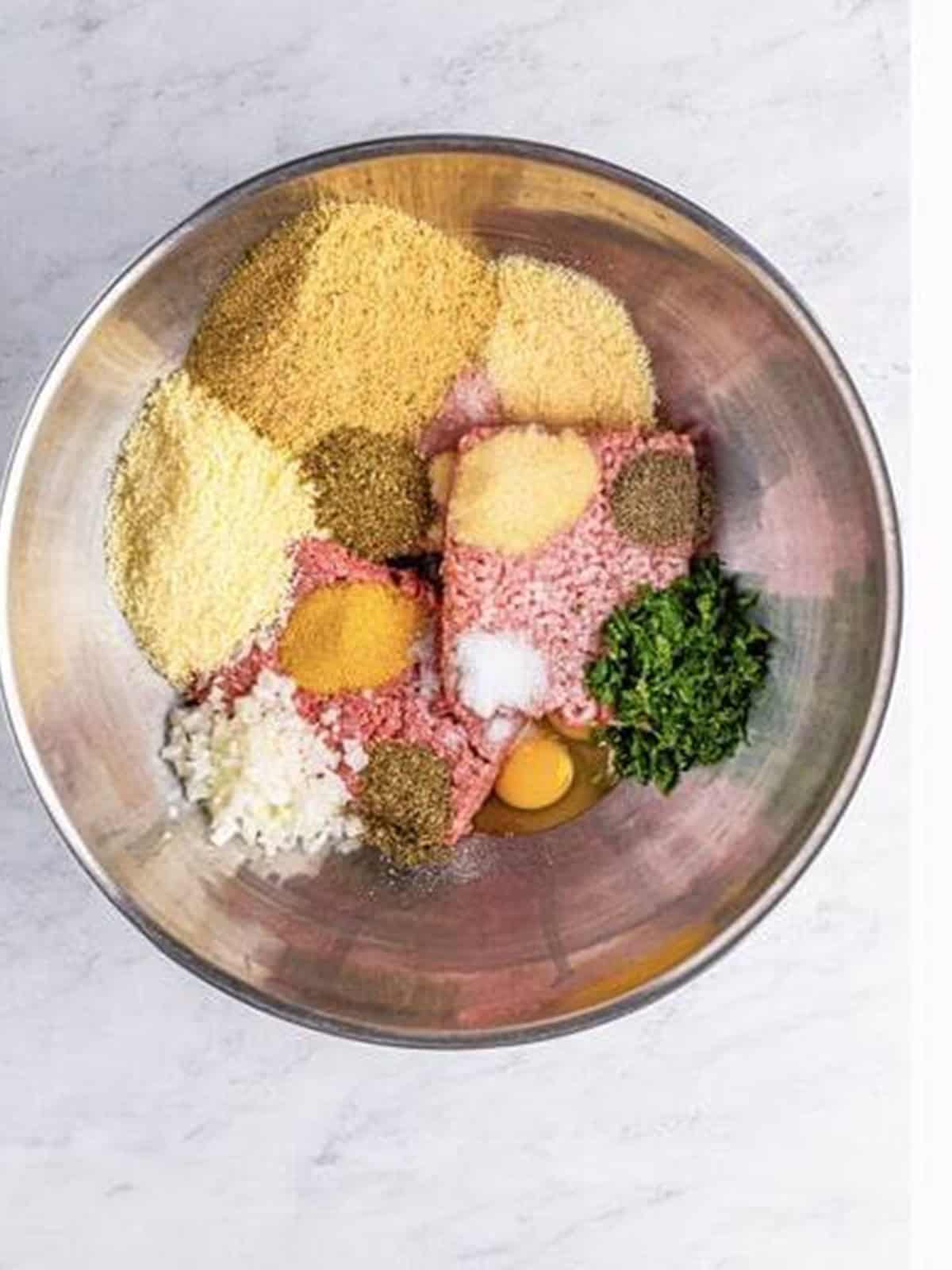 Ground beef, pork, veal, eggs, cheese, breadcrumbs, and seasonings combined in a bowl for Italian meatballs.