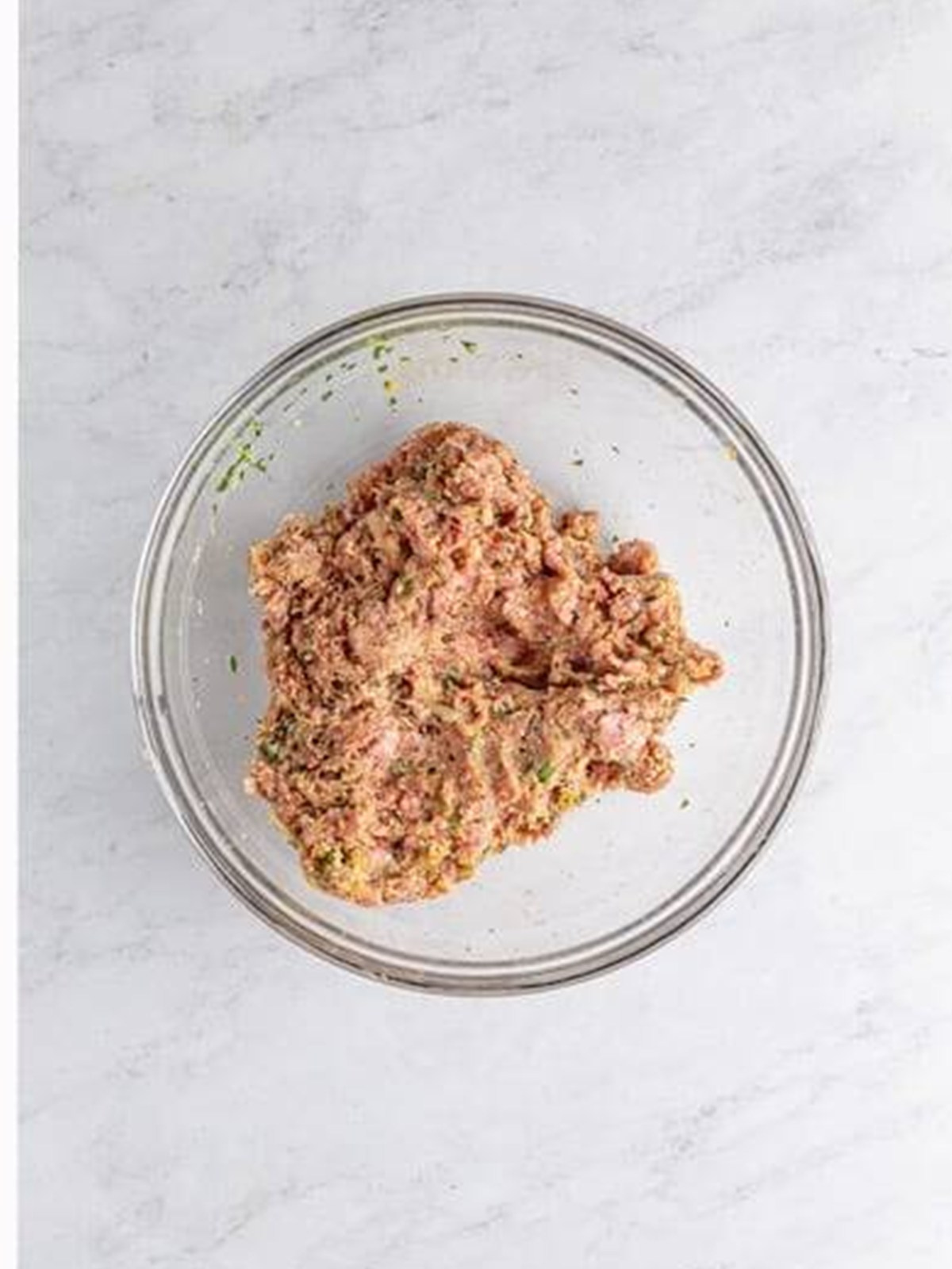 Mixing the seasoned meatball mixture in a glass bowl for Italian Wedding Soup.