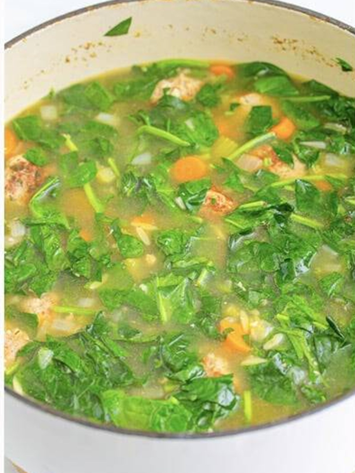 Stirring fresh spinach into the finished pot of Italian Wedding Soup.