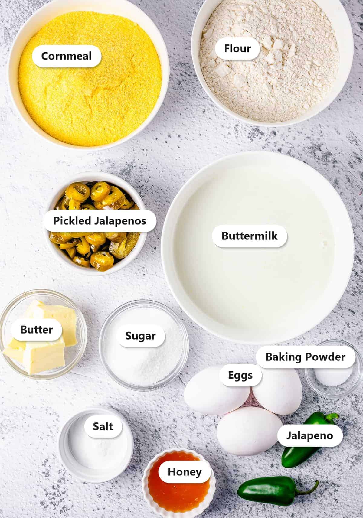 Labeled ingredients for jalapeno cornbread including cornmeal, flour, buttermilk, honey, eggs, and pickled jalapenos.