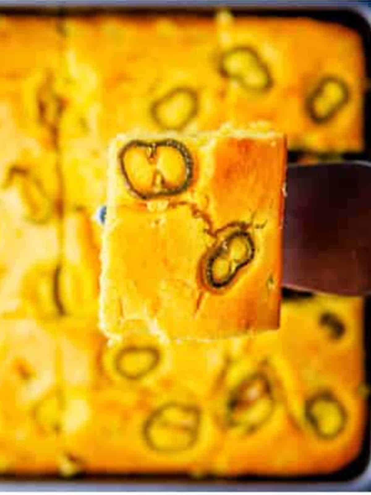 Baked jalapeno cornbread sliced into squares in the baking dish.