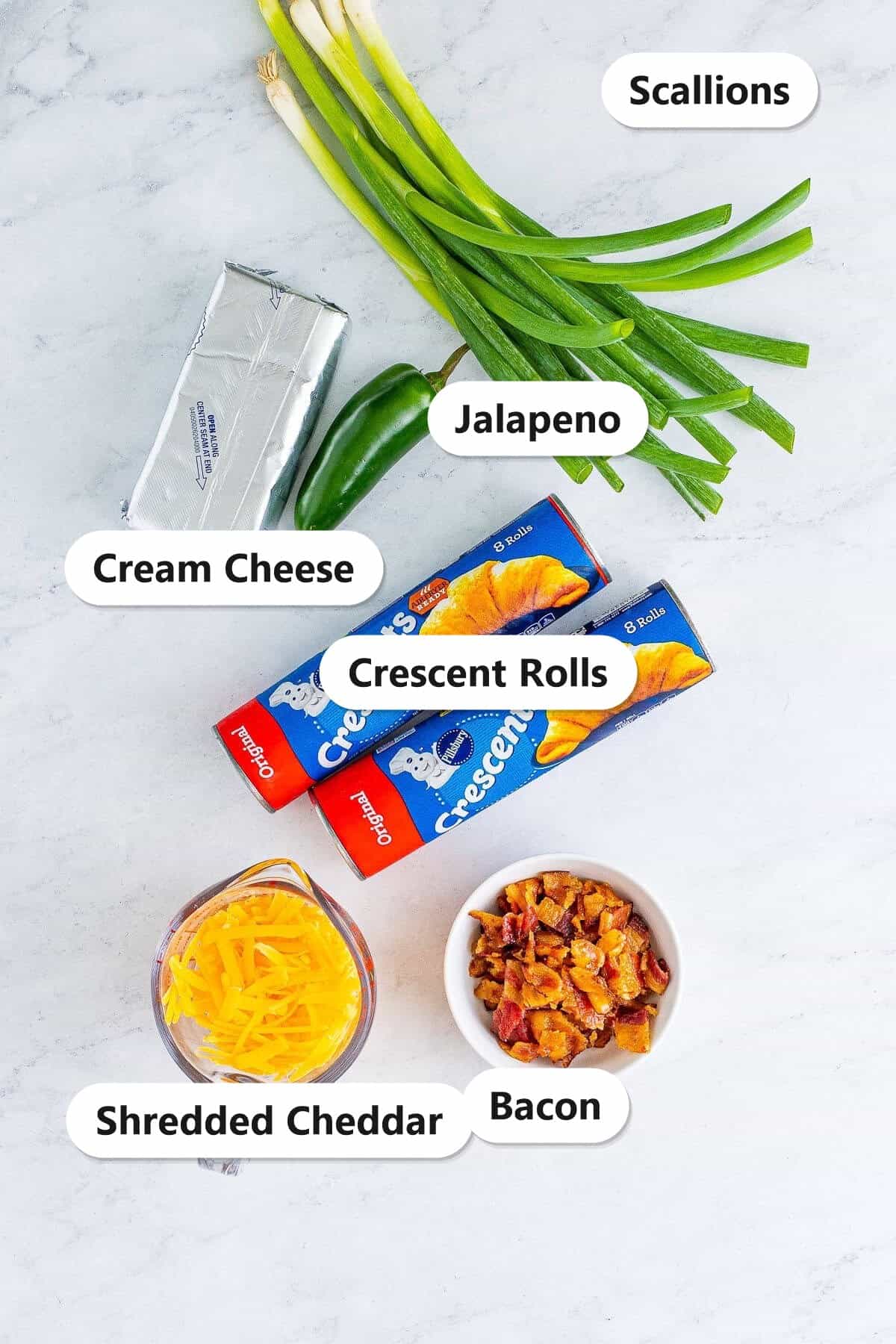 Labeled ingredient flatlay for Jalapeno Popper Crescent Rolls showing cream cheese, shredded cheddar, bacon, jalapeno, scallions, and Pillsbury crescent rolls.