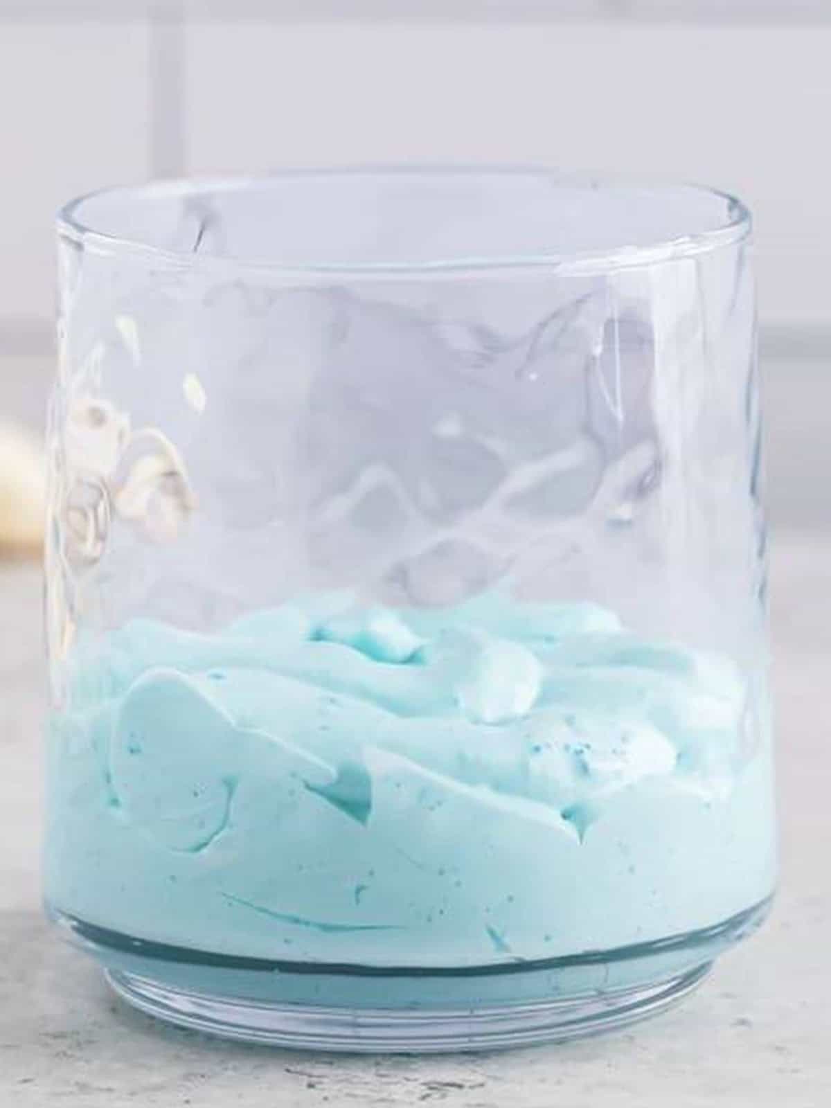 Blue jello mousse piped into the bottom of a small glass with dollops of whipped topping.