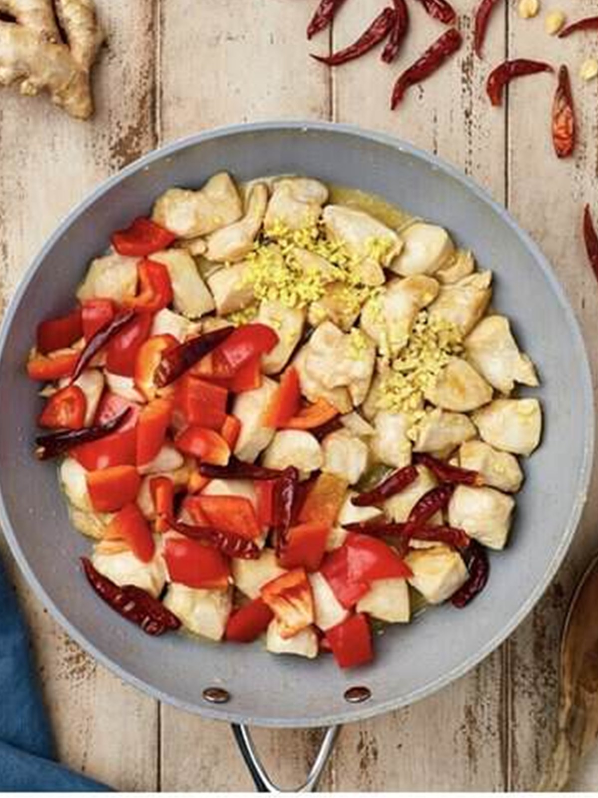 Adding red bell pepper, garlic, ginger, and dried chilies to the cooked chicken.