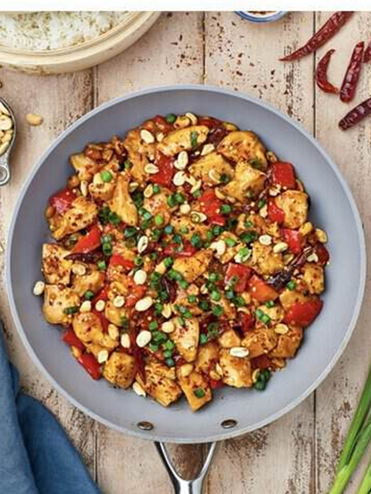 Finished kung pao chicken garnished with green onions and peanuts.