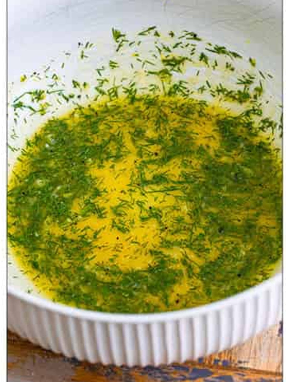 Whisked lemon dill dressing in a white bowl.