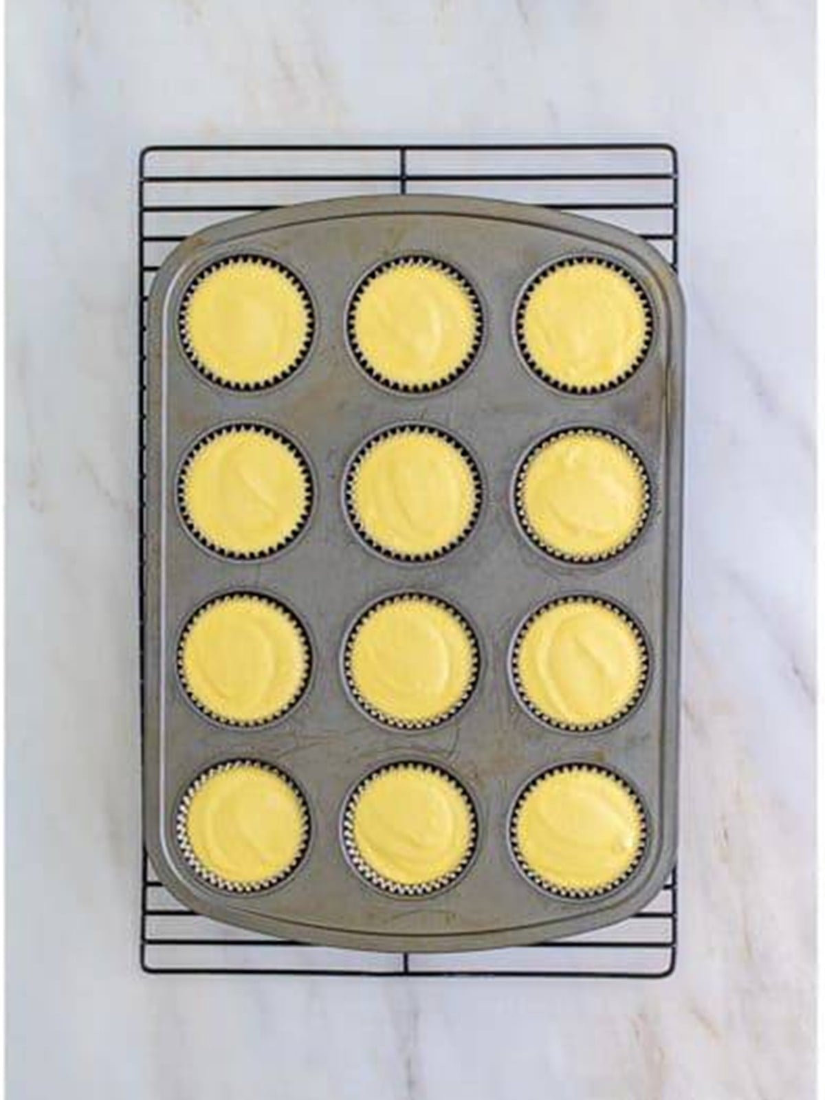 Baked mini Key Lime Cheesecakes cooling on a wire rack.