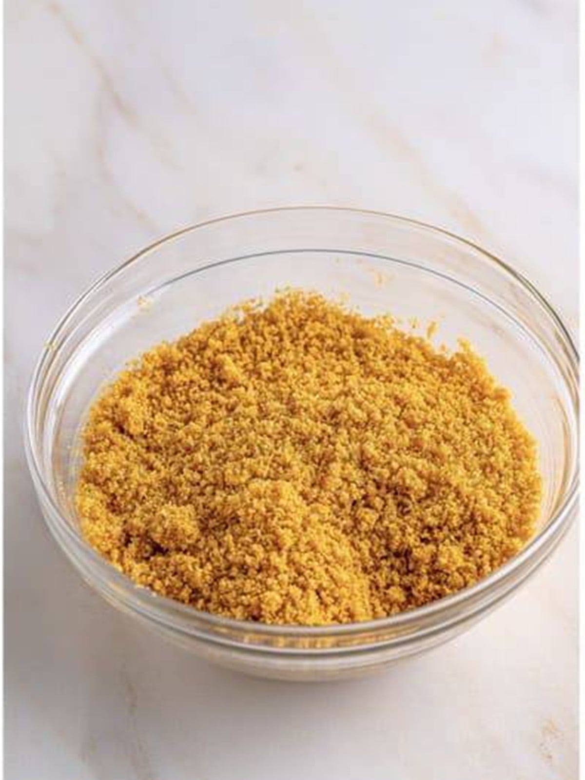 Graham cracker crumbs mixed with melted butter and sugar in a bowl for Key Lime Cheesecake crust.