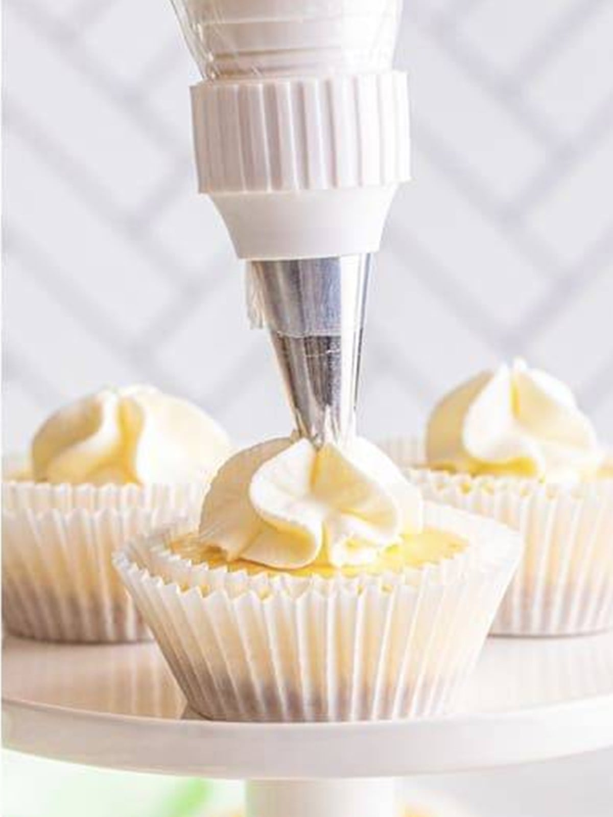 Piping whipped cream onto mini Key Lime Cheesecakes.
