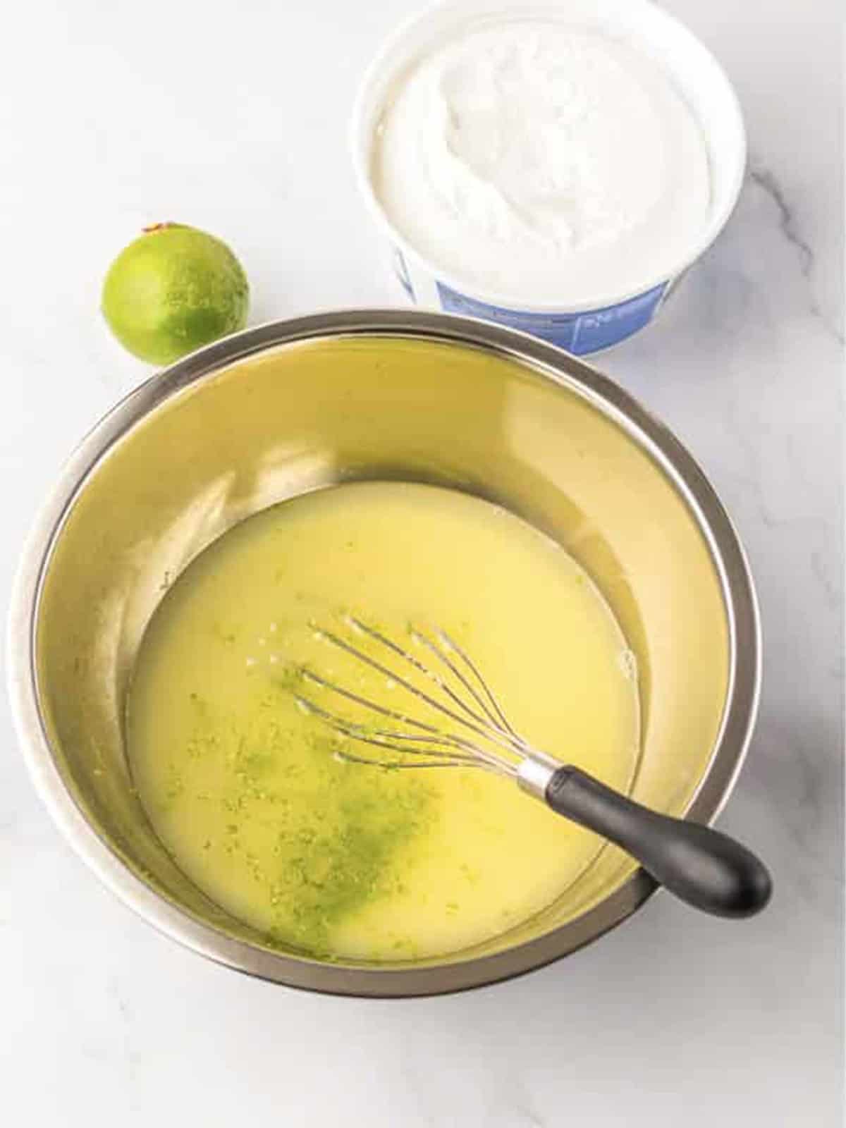 Key lime juice, zest, and sweetened condensed milk whisked together for Key Lime Fluff Salad.