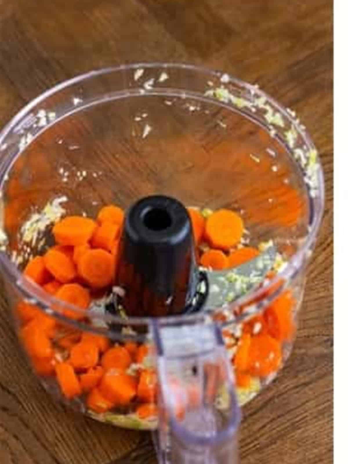 Sliced carrots in a food processor for coleslaw.