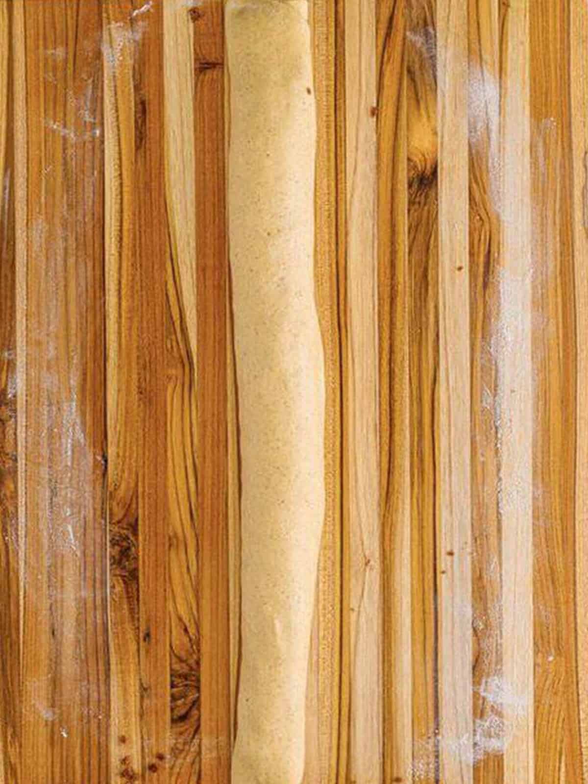 King cake dough rolled up with cinnamon filling into a long log on a cutting board.