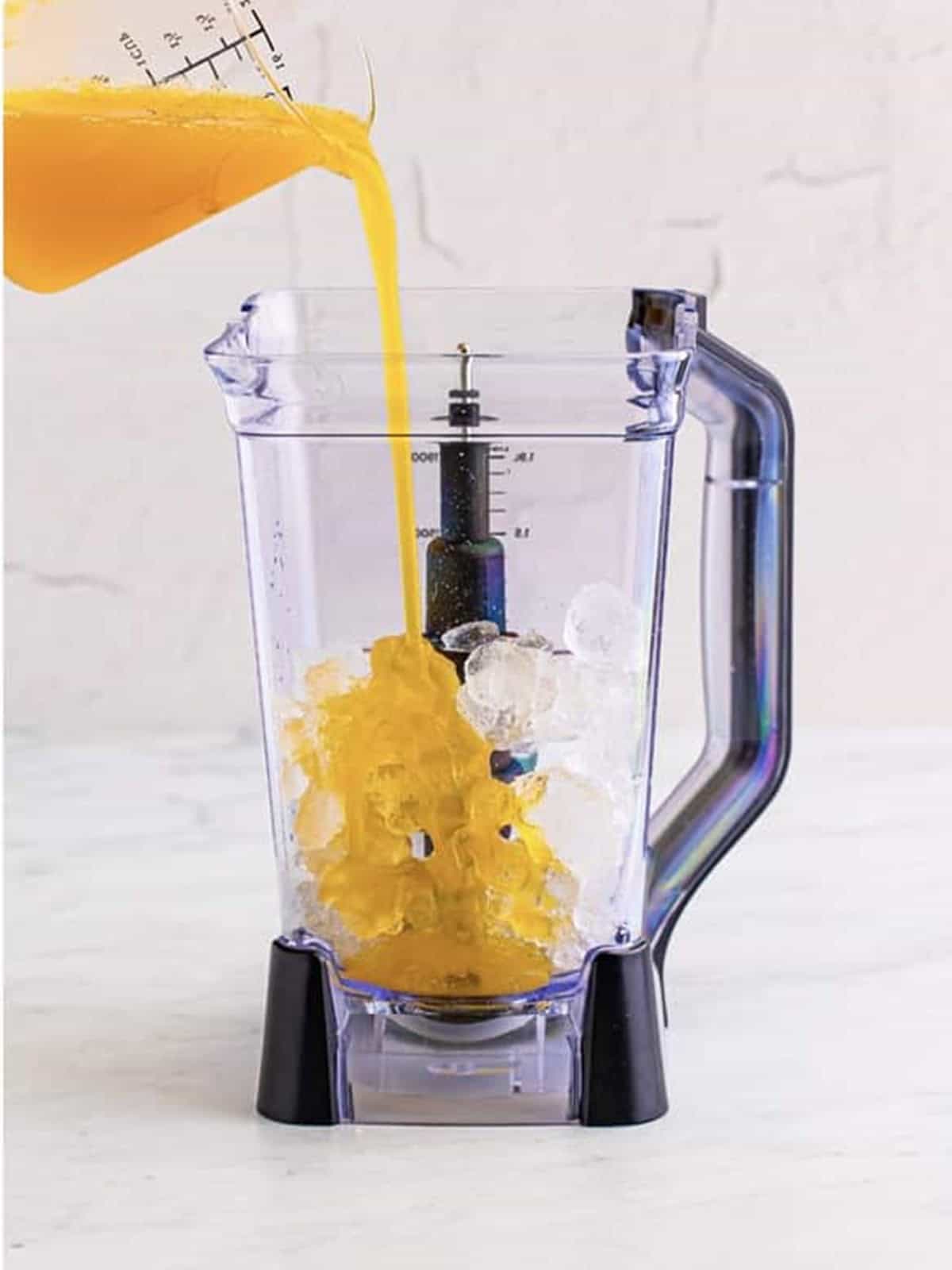 Mango cocktail mixer poured over ice into a blender for the Kiss on the Lips drink.