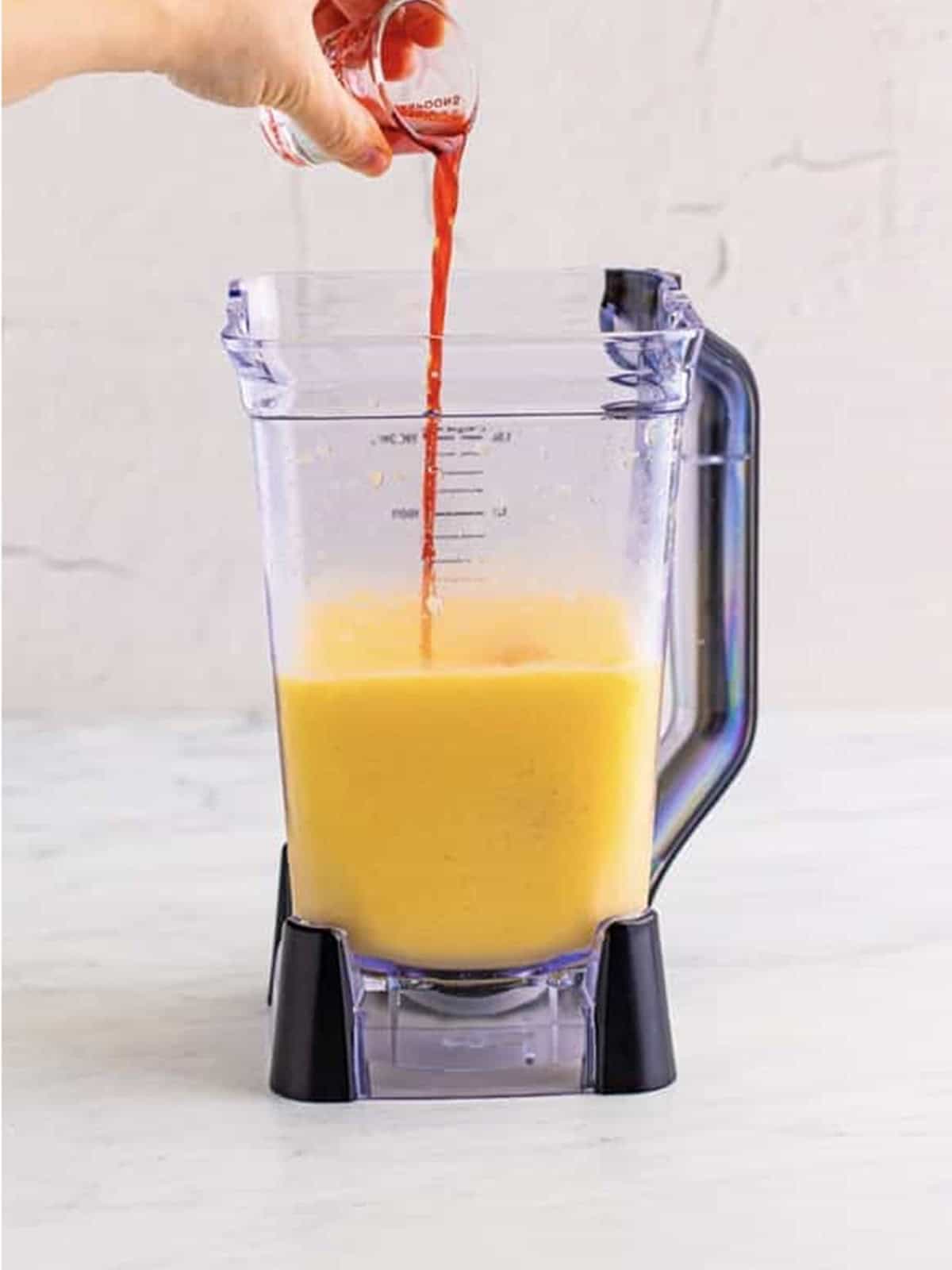 Red grenadine poured into the blended mango base for the Kiss on the Lips drink.