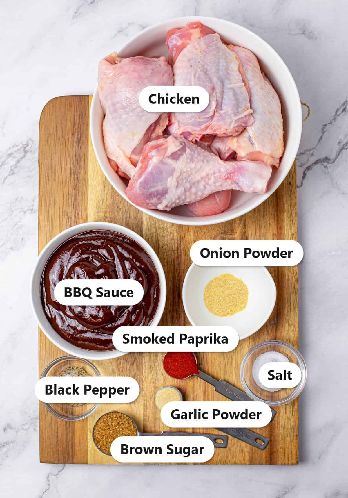 Labeled ingredients for slow cooker BBQ chicken including chicken pieces, BBQ sauce, brown sugar, smoked paprika, garlic powder, onion powder, salt, and black pepper.