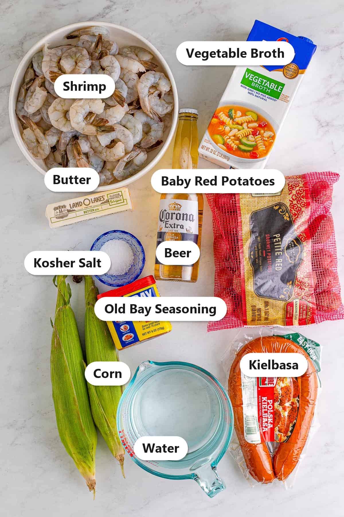 Labeled ingredients for shrimp boil including shrimp, kielbasa, baby red potatoes, corn, vegetable broth, beer, old bay seasoning, and butter.