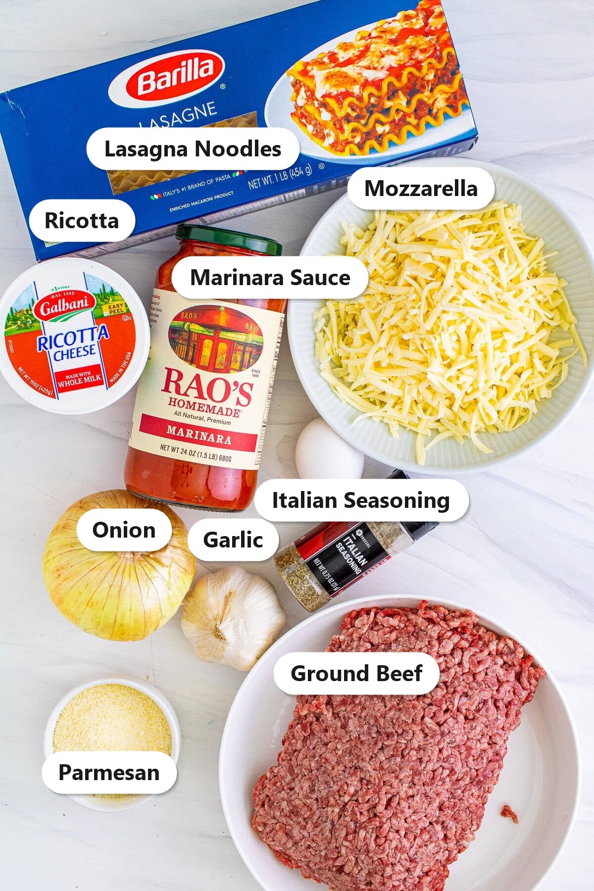 Ingredients for lasagna roll-ups including lasagna noodles, marinara, ricotta, mozzarella, parmesan, ground beef, onion, garlic, and Italian seasoning.