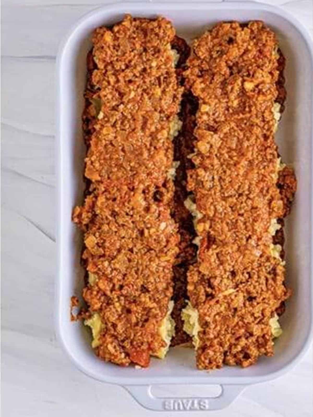 Cheese filling and meat sauce spread over a noodle in a dish for lasagna roll ups.