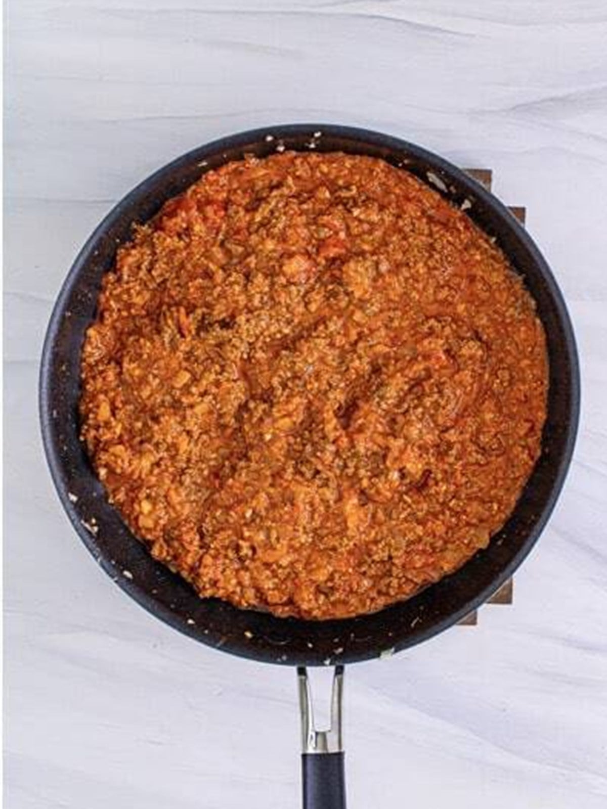 Ground beef simmered with marinara into a meat sauce in a skillet.