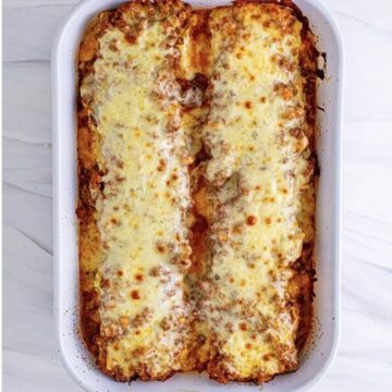 Lasagna roll-ups topped with mozzarella and parmesan before baking.