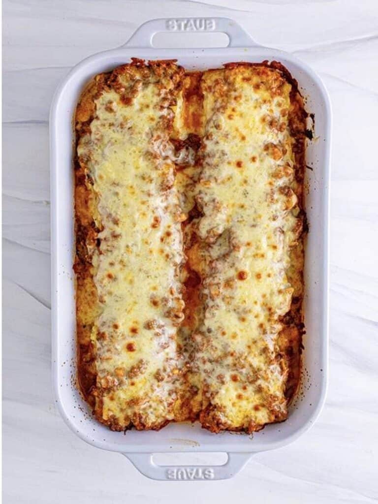 Lasagna roll-ups topped with mozzarella and parmesan before baking.