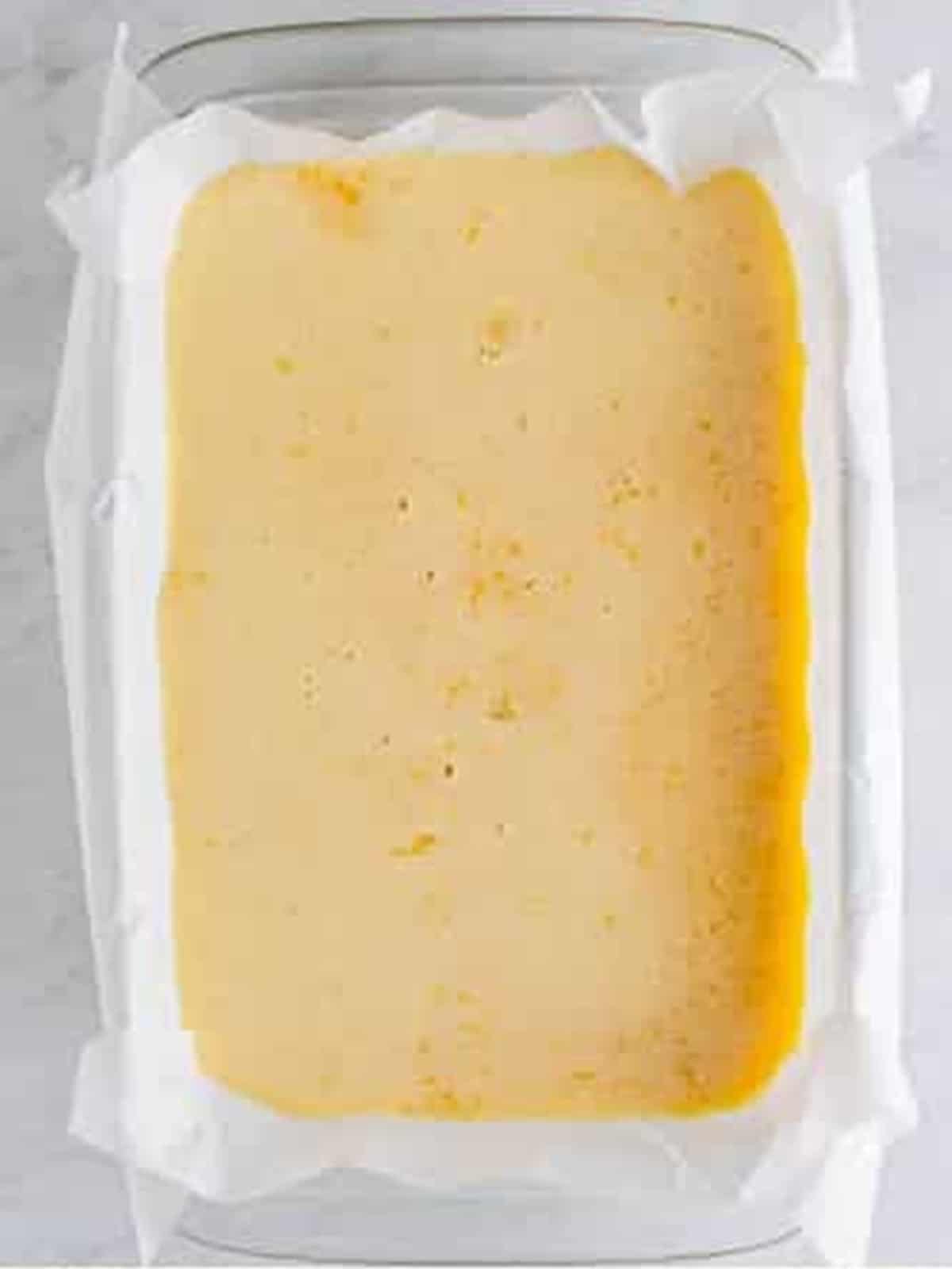 Lemon filling poured over the shortbread crust before baking the lemon bars.