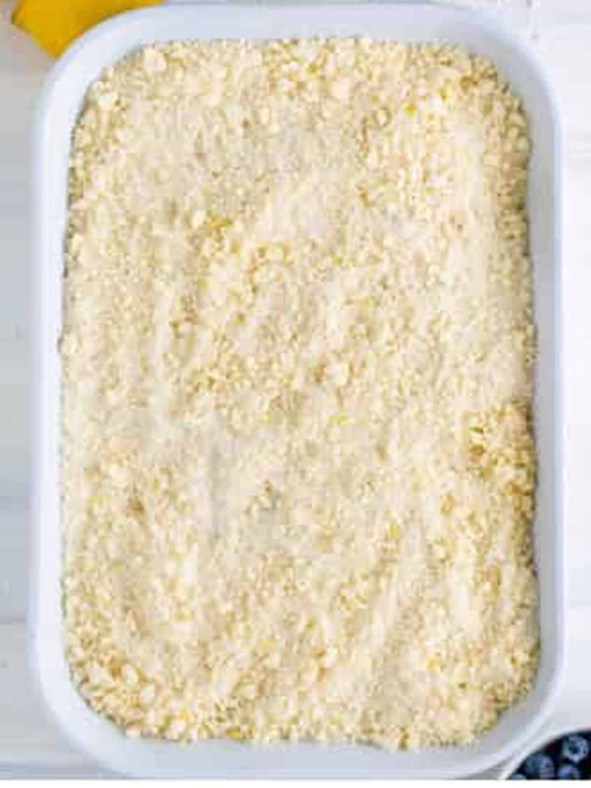 Layered lemon blueberry coffee cake topped with streusel in a baking pan.